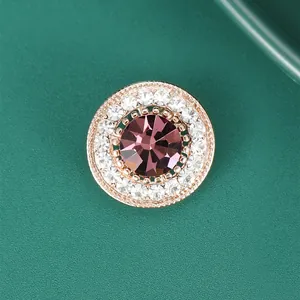 Detail of round rose gold brooch with a large purple crystal and clear zircon accents