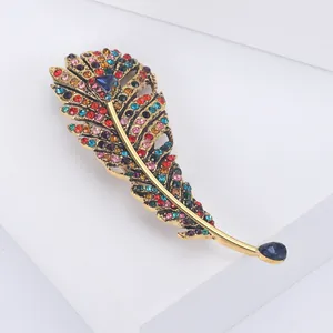 Macro detail of golden feather brooch with multi-color rhinestones on white block