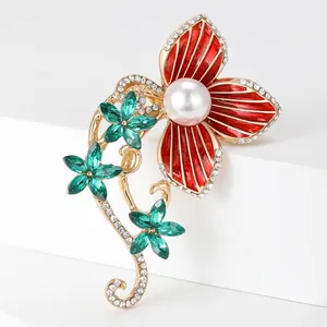 Detailed macro view of a red floral brooch with white pearl and green crystal accents
