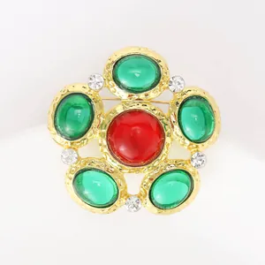 Close-up of vintage flower brooch with hammer texture and colored gemstone inlay