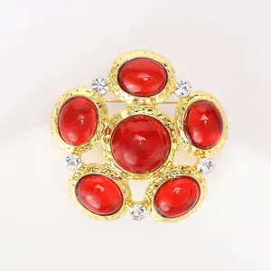 Detail of vintage gold flower brooch with red cabochon stones and crystal accents