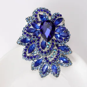 Detailed macro view of a floral brooch featuring teardrop blue crystals and silver alloy