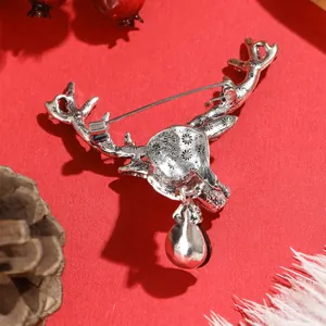 Silver vintage reindeer head brooch with intricate star engraving on festive red background