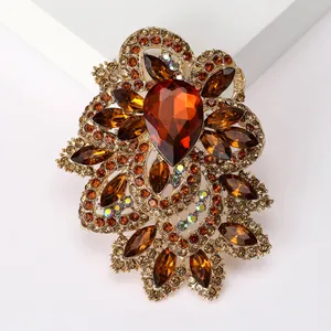 Detailed view of amber teardrop crystal brooch with intricate gold metal filigree