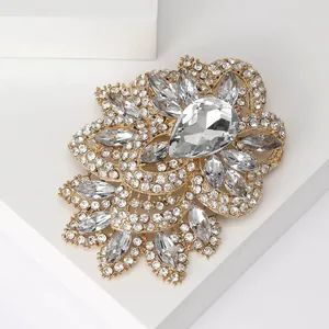 Macro view of crystal glass brooch with large pear-cut stone and gold-plated floral frame
