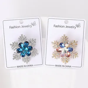 Detailed close-up of crystal snowflake brooches in blue and multicolor on a display card