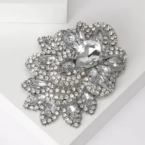 Detailed close-up of a silver flower brooch featuring crystal rhinestones on a white stand