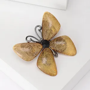 Makro-Detail einer bernsteinfarbenen Schmetterlingsbrosche mit schwarzem Edelstein