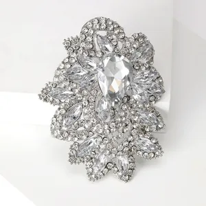 Detailed close-up of sparkling crystal waterdrop brooch on white geometric stand