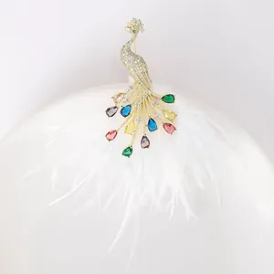 Detailed close-up of peacock brooch with colorful teardrop gems on soft white feathers