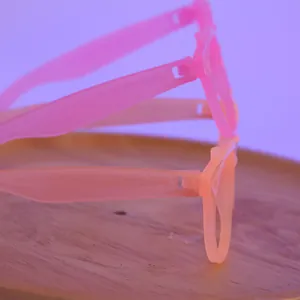 Macro shot of three glowing fluorescent glasses stacked on a wooden tray with purple lighting