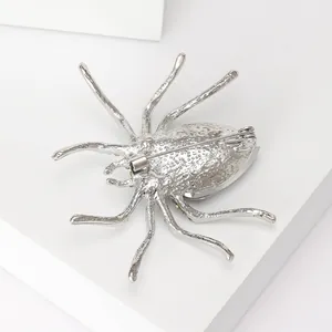 Macro detail of silver spider brooch with faceted crystal on a geometric display