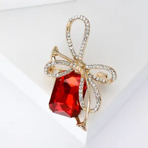 Macro detail of a golden bow brooch with a large red crystal and pavé rhinestones