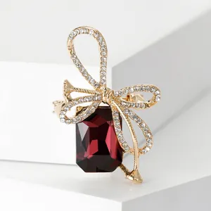 Detailed macro of golden bow brooch with deep red rectangular crystal and pavé stones