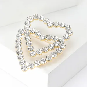 Macro detail of intertwined golden heart brooches with shimmering crystal pavé inlay
