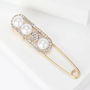 Makroaufnahme einer eleganten Goldbrosche mit großen weißen Perlen und Strasssteinringen