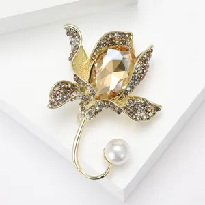Macro detail of golden flower brooch with amber gemstone, pavé crystals and white pearl