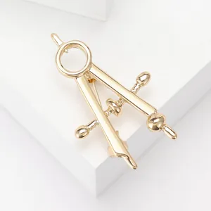 Macro detail of golden compass brooch with a polished mirror finish on white cubes