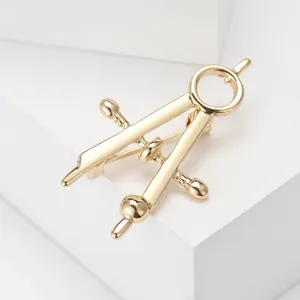 Detailed view of a polished golden compass brooch on a white geometric display stand