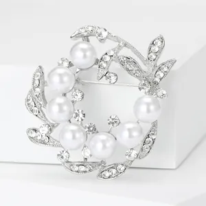 Vue détaillée d'une broche couronne en perles argentées avec cristaux et épingle