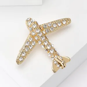 Détail macro d'une broche avion dorée ornée de strass brillants sur métal poli