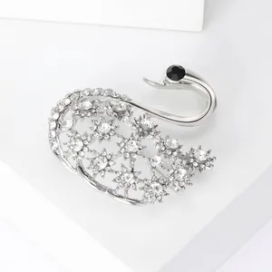 Détail macro d'une broche cygne argentée avec motifs floraux et cristaux étincelants