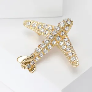 Vue macro d'une broche avion dorée avec strass blancs étincelants sur un socle géométrique