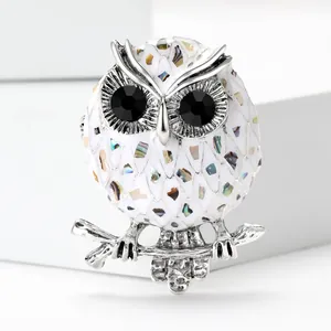 Detailed close-up of an owl brooch with iridescent shell inlay and black crystal eyes