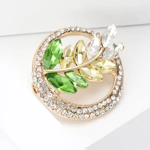 Detail of wheat ear brooch with gold base and colorful crystals on white geometric background