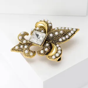 Detail of vintage gold brooch with white pearls and large square crystal on white stand