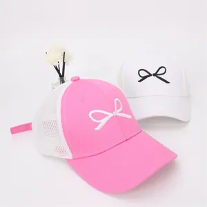 Detail of pink and white breathable mesh baseball caps with embroidered bow decorations