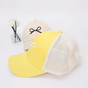 Detail of breathable mesh baseball caps with bow embroidery in yellow and cream