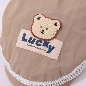 Detail of light brown breathable mesh fabric with plush bear patch and Lucky label