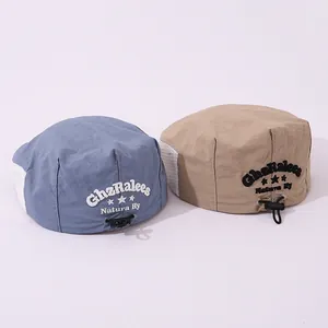 Detail view of khaki and grey-blue children's berets with breathable mesh and embroidery