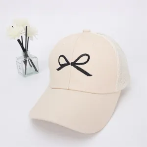 Close-up of beige kids baseball cap featuring breathable white mesh and bow embroidery