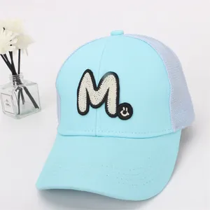Close-up of light blue kids baseball cap featuring M letter embroidery and grey mesh back