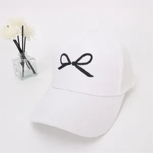 Detail of white mesh baseball cap featuring a black bow embroidery and breathable back