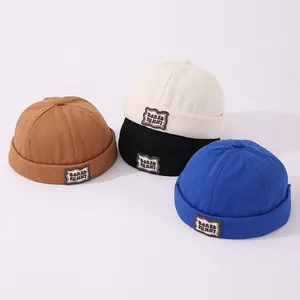Detalle de cuatro gorros docker de algodón para niños con parches bored funny