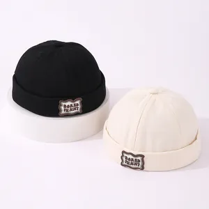 Detalle de gorros docker de algodón negro y beige con parche de cuero Bored Funny bordado