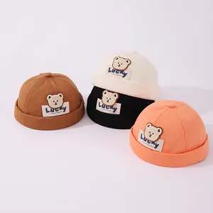 Detalle de gorros de algodón para niños con parches de oso en 3D y etiquetas LUCKY tejidas