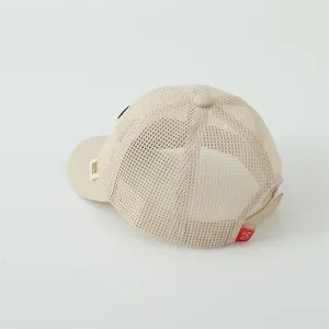 Detail of breathable beige mesh baseball cap with red brand label and adjustable back