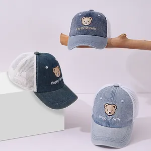 Close-up of three blue denim mesh baseball caps featuring embroidered bears and mesh panels