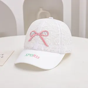 Detail of white lace baseball cap with pink bow and sports embroidery for girls