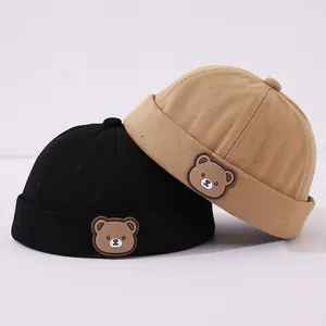 Detalle de gorros de estibador para niños en negro y caqui con parche de oso en 3D