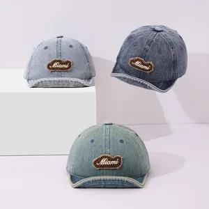 Three shades of vintage denim baseball caps with Miami embroidery on a display stand