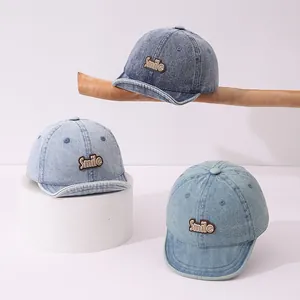 Detailed view of three denim baby baseball caps with Smile patch in multiple blue washes