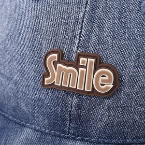 Detailed close-up of brown Smile rubber patch on blue denim kids baseball cap