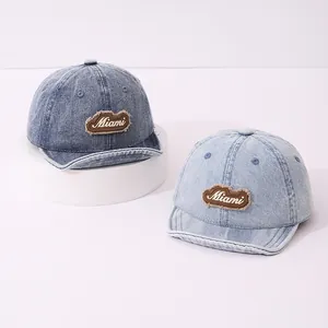 Detail of dark and light blue denim kids baseball caps with Miami patch embroidery