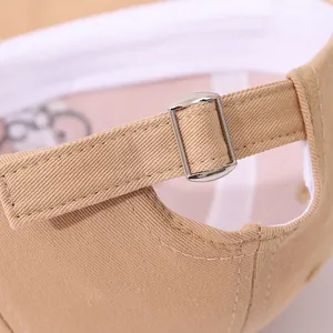 Détail de la boucle métallique réglable et couture sur casquette bébé en coton beige