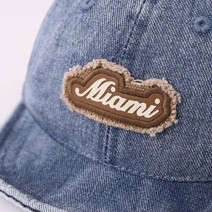 Detail of blue denim baseball cap featuring a brown Miami patch with white stitching